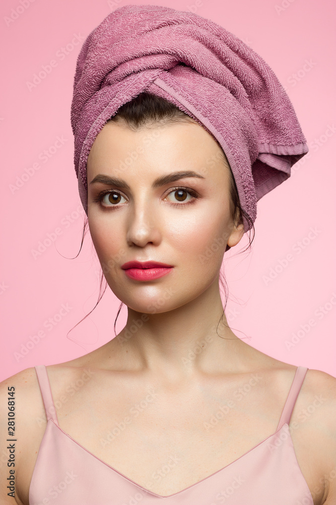Beauty Woman face with hands. Beautiful Portrait Spa model Girl with Perfect Fresh Clean Skin. Female looking at camera and smiling. Youth and Skin Care Concept. Pink towel on the head, space for text Beauty Woman face with hands. Beautiful Portrait Spa model Girl with Perfect Fresh Clean Skin. Female looking at camera and smiling. Youth and Skin Care Concept. Pink towel on the head, space for text