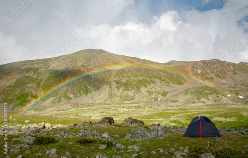 Tourist tent on a background of green mountain slopes with a rainbow, Teberda, Karachay-Cherkessia, Russia