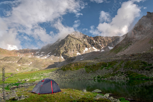 Tourist tent stands next to a high-mountain lake on the background of Mount Dzhalkaush  height 3283  Teberda  Karachay-Cherkessia  Russia