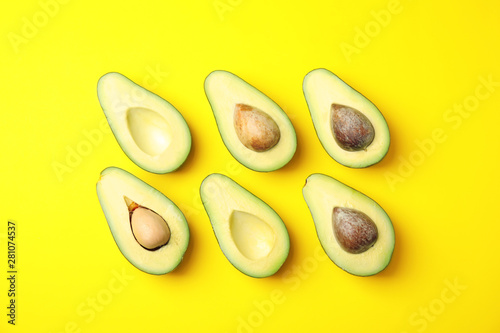 Cut fresh ripe avocados on yellow background, flat lay