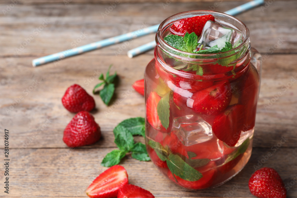 Mason jar of refreshing drink with strawberry and mint on wooden table, space for text Mason jar of refreshing drink with strawberry and mint on wooden table, space for text