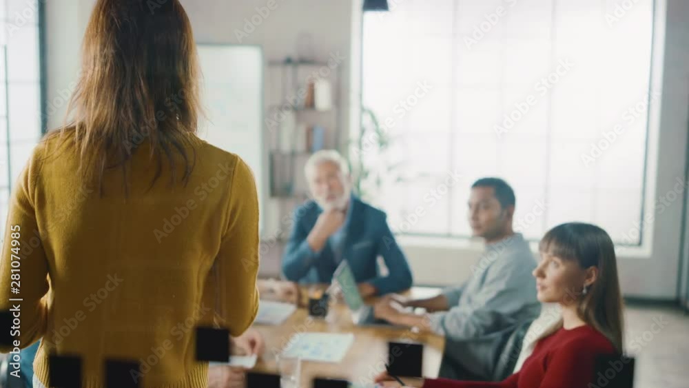 In the Meeting Room Young and Beautiful Female Junior Associate Makes a Speech / Report to a Board of Directors Member who are Sitting at the Conference Table. Modern Startup in the Stylish Office In the Meeting Room Young and Beautiful Female Junior Associate Makes a Speech / Report to a Board of Directors Member who are Sitting at the Conference Table. Modern Startup in the Stylish Office