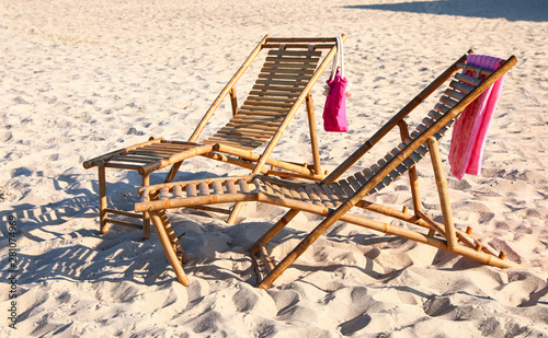 Empty wooden sunbeds and beach accessories on sandy shore