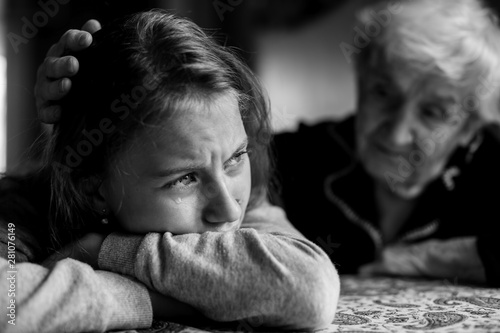 Old lady grandma comforting a crying little girl granddaughter. Black and white photo.