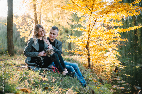 Beautiful young couple resting in autumn park. autumn concept. Loving couple resting with their cat.