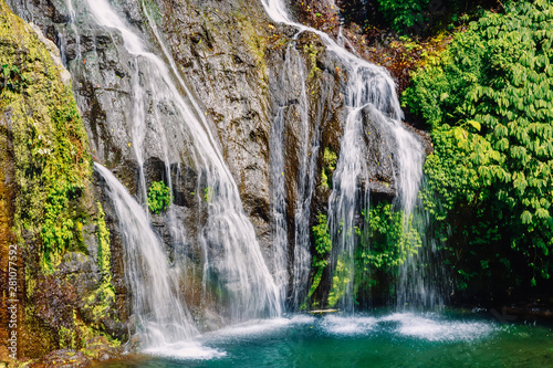 Waterfall with crystal blue water and rainbow in tropics