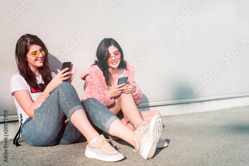 Two beautiful young women using their smartphones