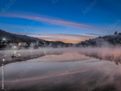 Lake view morning of the mist rising up from the water around with the hill, mountain and blue sky background, sunrise at Ban Rak Thai, Mae Hong Son, northern of Thailand. © Yuttana Joe