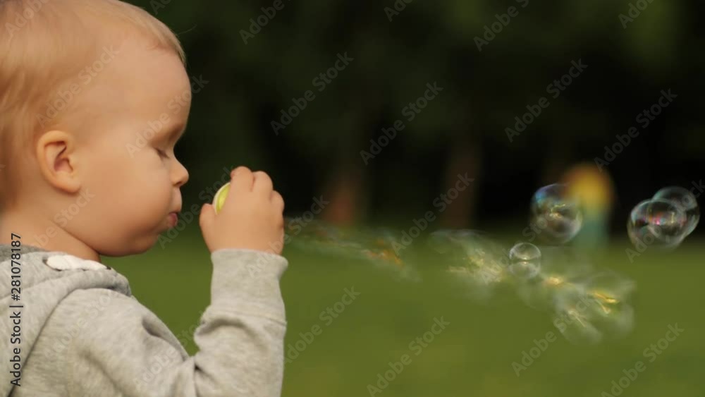 Enthusiastic little baby boy blowing soap bubble having positive emotion medium close-up side view Enthusiastic little baby boy blowing soap bubble having positive emotion medium close-up side view