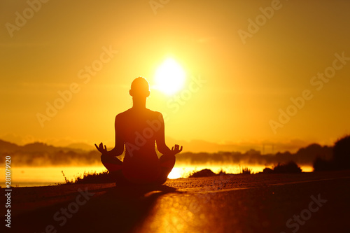 Woman silhouette practicing yoga exercise at sunrise © Antonioguillem