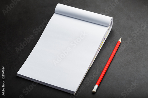 Notepad with a red pencil on a black stone plate background, for education, recording goals and deeds