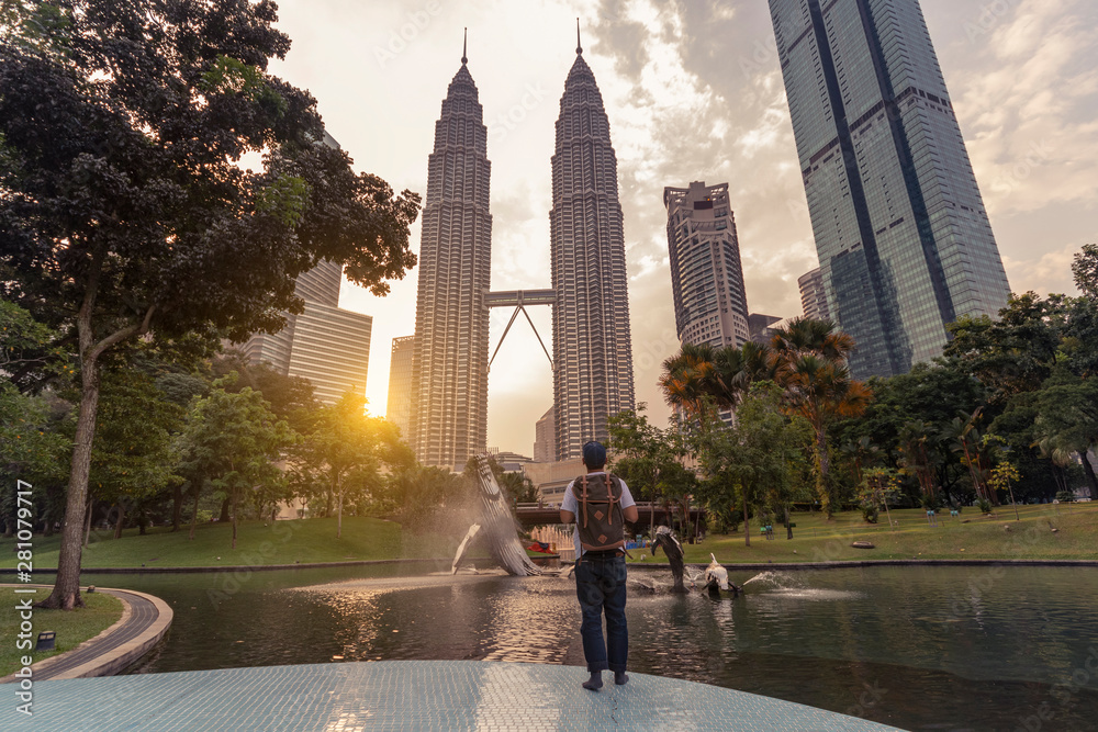 Naklejka premium Mężczyzna z plecakiem podróżuje i zwiedza Landmark Twin Tower w Kuala Lumpur w Malezji.