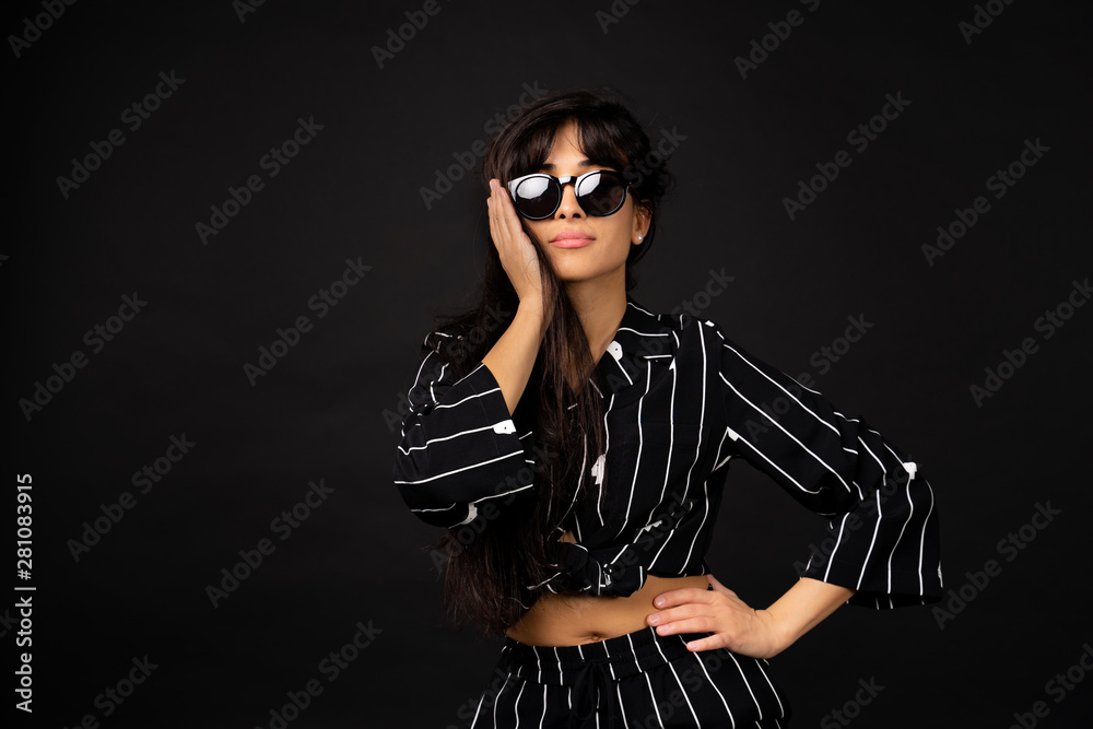 Young business girl in a black suit posing for a photo on a black background.