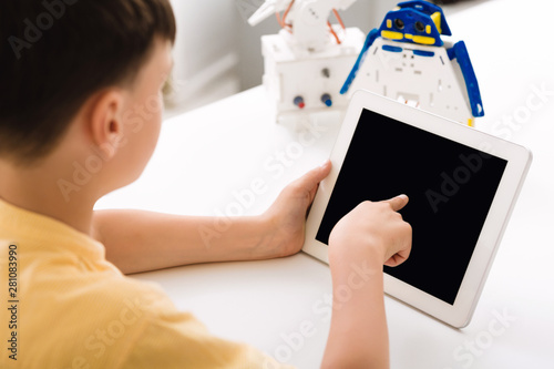Boy programming electric toy with tablet computer