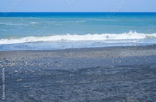 Fototapeta Naklejka Na Ścianę i Meble -  Ocean coast with black volcanic sand on the island of Bali, Indonesia.