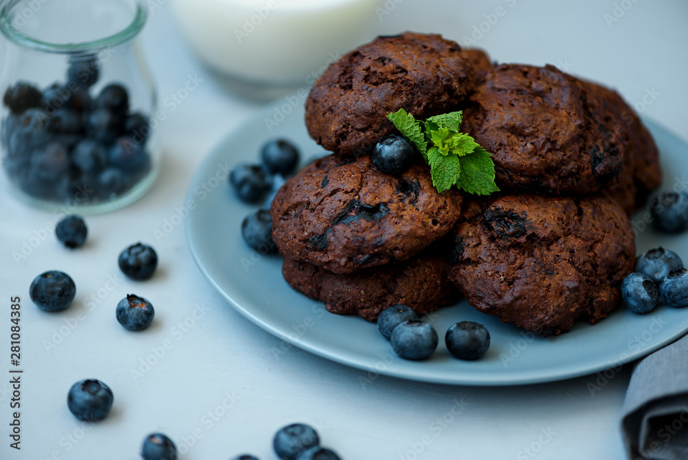 Chocolate cookies with chocolate chips and blueberry on gray wooden background. Summer food. Soft focus. Chocolate cookies with chocolate chips and blueberry on gray wooden background. Summer food. Soft focus.