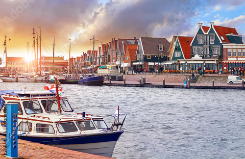Volendam, Netherlands. Luxury yacht parked by pier in bay of North Sea on evening sunset under traditional old town. photo
