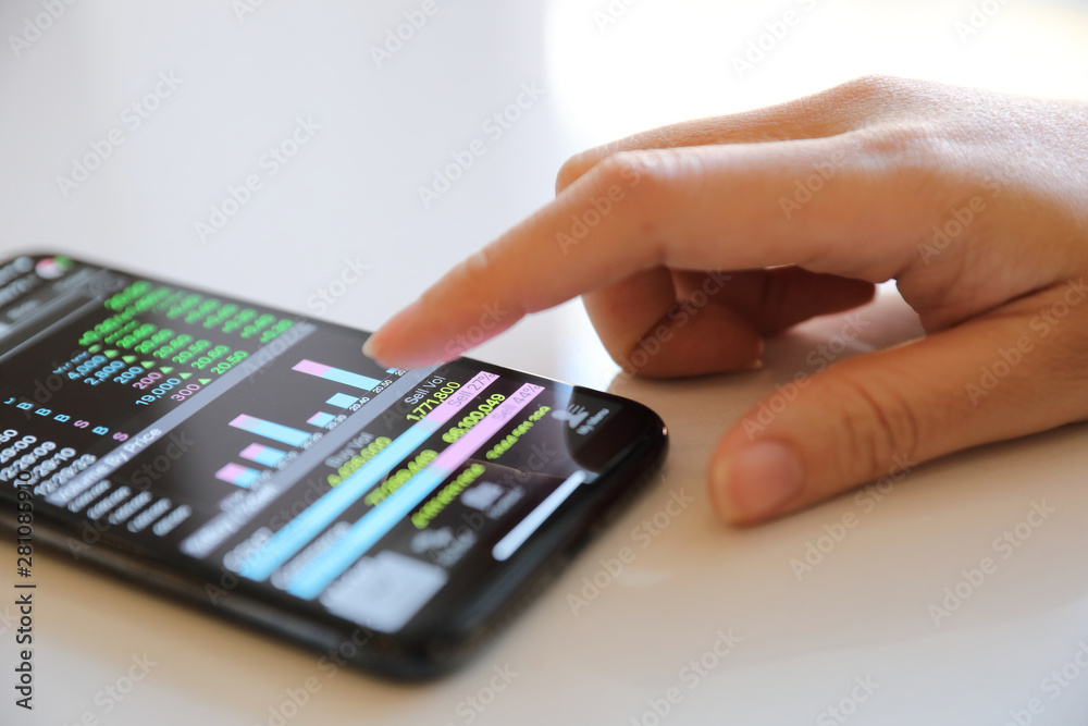 Female hand with smartphone trading stock online in coffee shop , Business concept Female hand with smartphone trading stock online in coffee shop , Business concept