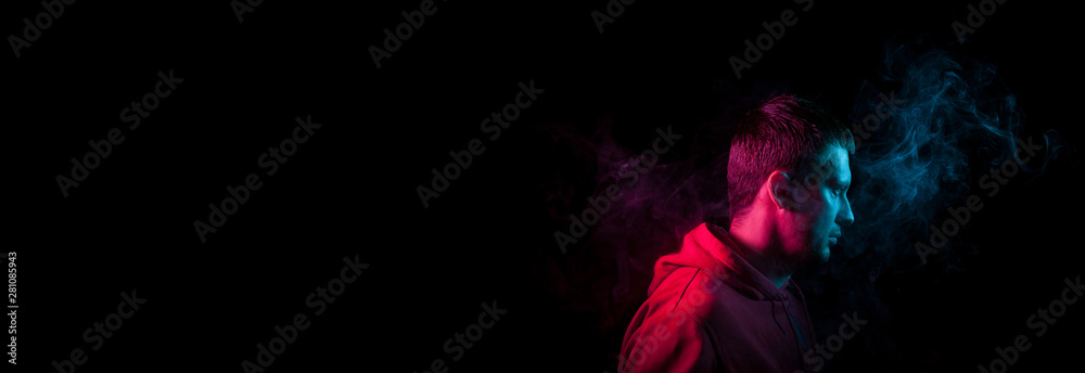 Banner with a portrait of a guy in profile face standing back to black background with a feeling of sadness and loneliness, around his head a cloud of blue and pink smoke. The soul and feelings of man