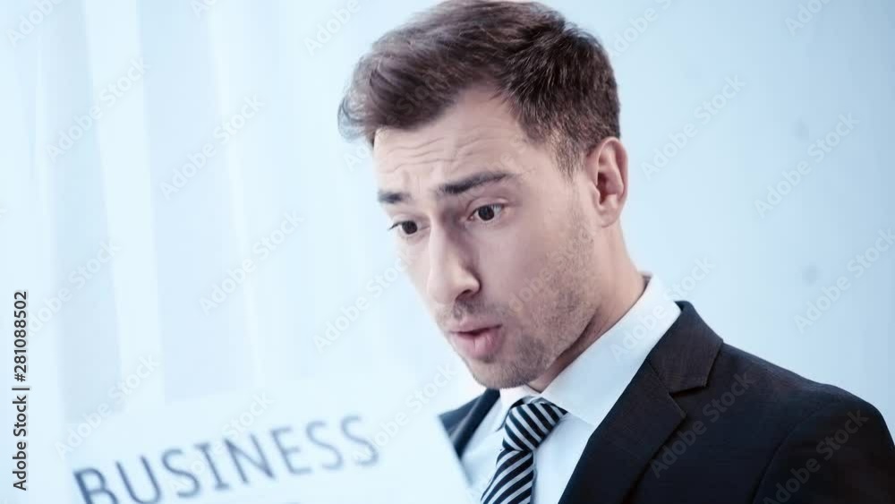 handsome, surprised businessman reading business newspaper in office handsome, surprised businessman reading business newspaper in office