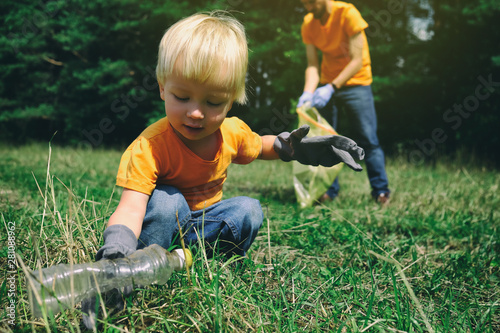 Volunteers activists child and his father in gloves tidying up rubbish in park or forest. Save environment concept. Stop plastic pollution