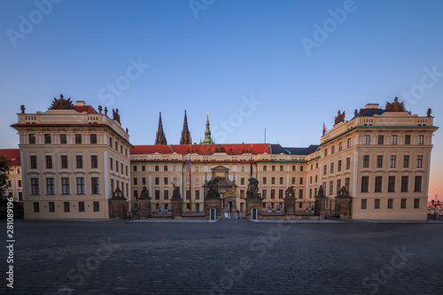 Entrance with forecourt to Prague Castle from Hradschin Square. Historic building with fence and Titans sculptures in the evening with blue sky