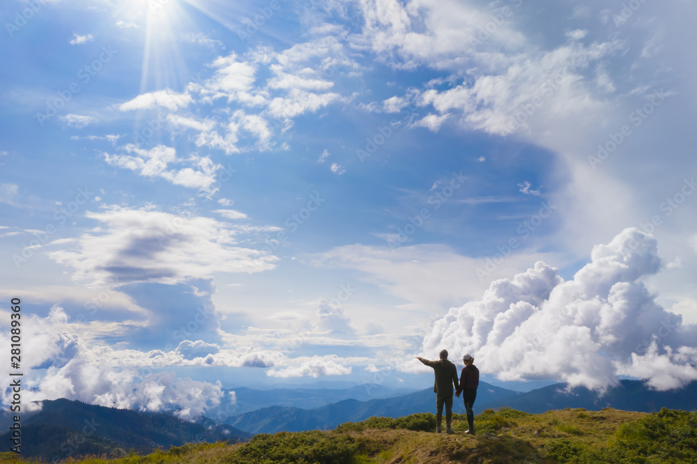 The couple standing on a mountain against beautiful clouds - obrazy, fototapety, plakaty 