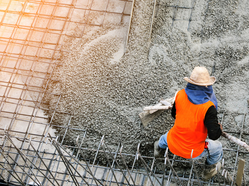 Top view of builders in orange shirt pouring concrete works on the construction site photo