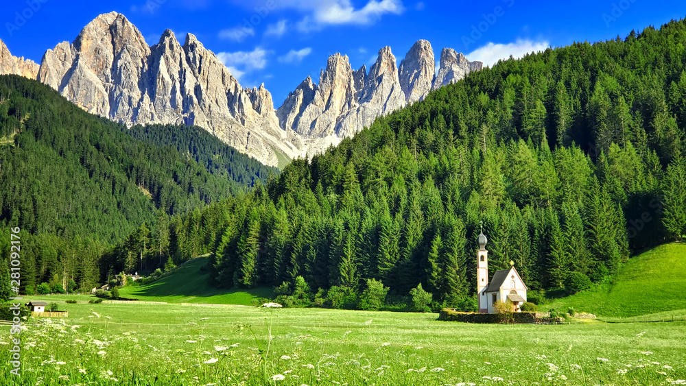 The church of St. Johann under the jagged peaks of the Dolomites during summer, Italian Alps