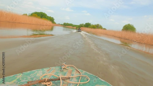 Two Motorboats follow one another through the calm water of a river channel at high speed. Spring flood in the Volga river delta. Russia, Astrakhan region, near the town of Kamyzyak. photo