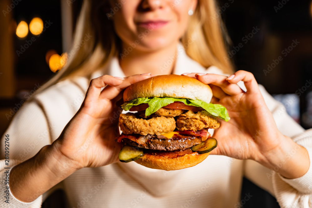 .Young woman eating burger in restaurant .Young woman eating burger in restaurant