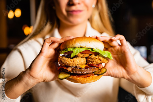 .Young woman eating burger in restaurant
