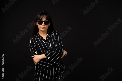 Young business girl in a black suit posing for a photo on a black background.
