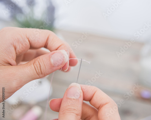 Close-up of woman s hand inserting thread in the needle