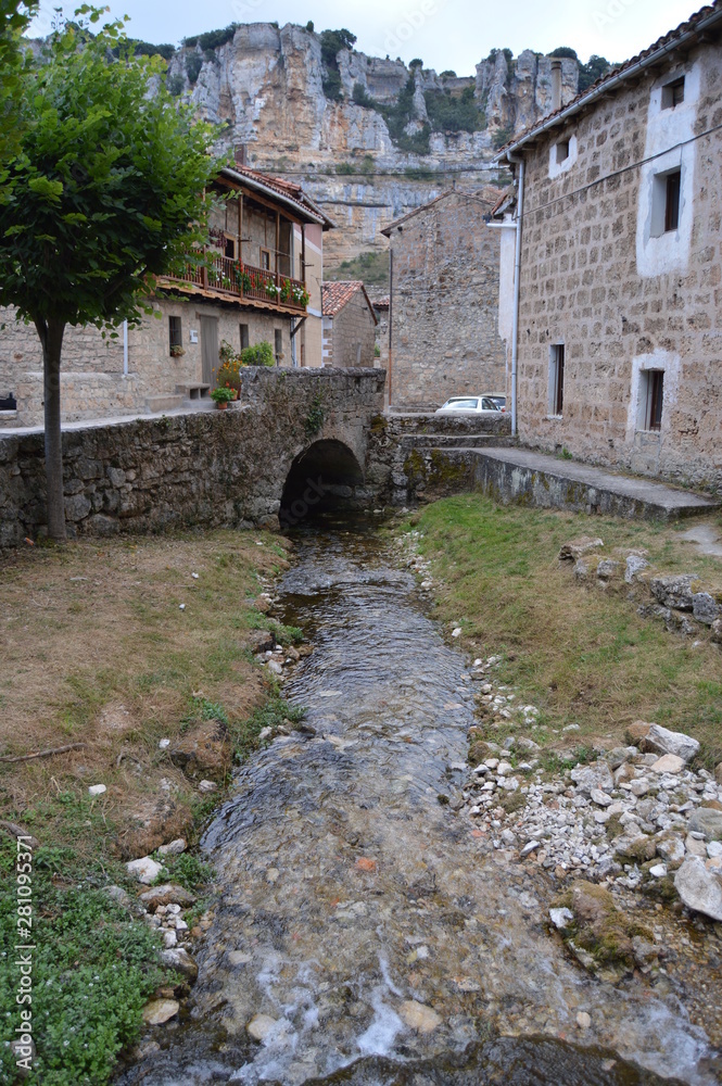 Stream Leaving Through A Bridge In The Middle Of The Streets In Orbaneja Del Castillo. August 28, 2013. Orbaneja Del Castillo, Burgos, Castilla Leon, Spain. Vacation Nature Street Photography.