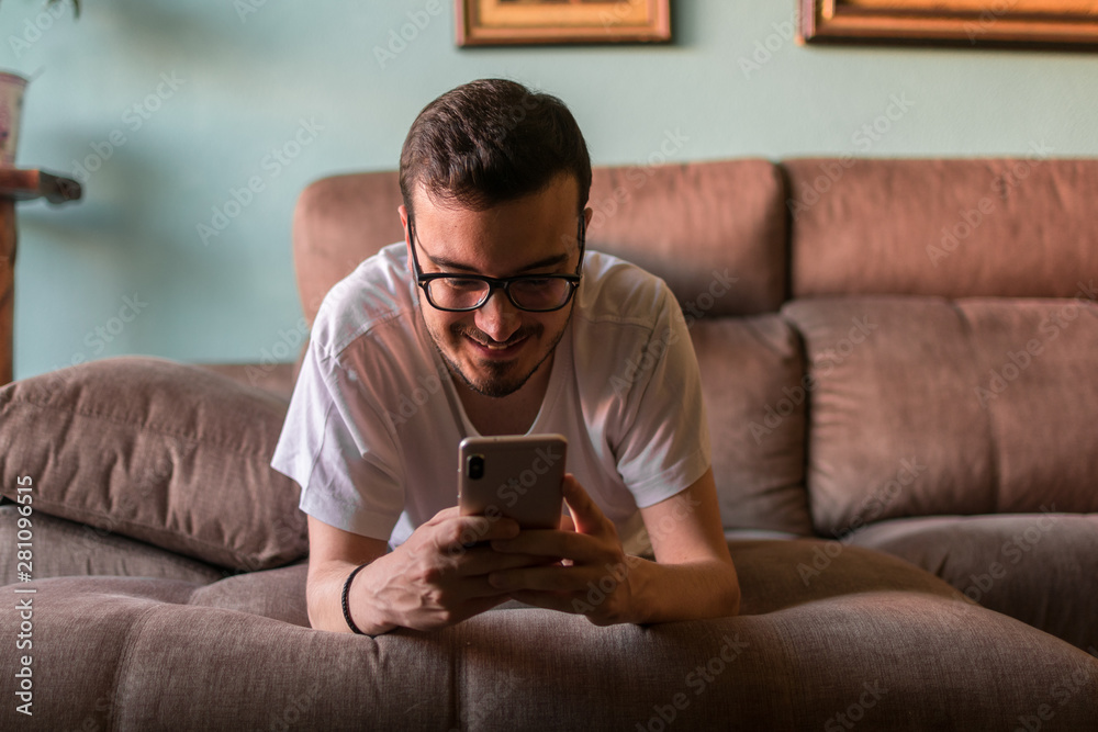 Man using mobile phone while lying on sofa at home