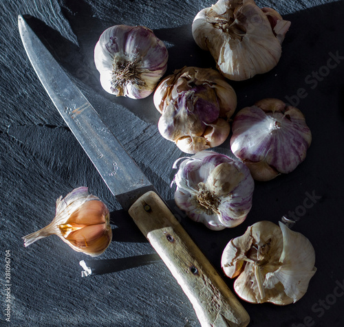 Unas cuantas cabezas de ajo morado junto a un cuchillo antiguo photo