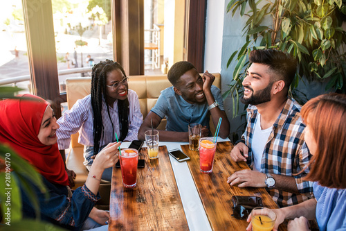 Group of happy friends drinking juice and lemonade at cafe.