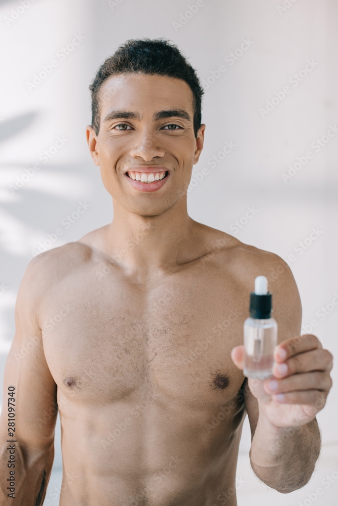 handsome muscular man showing bottle with serum and looking at camera handsome muscular man showing bottle with serum and looking at camera