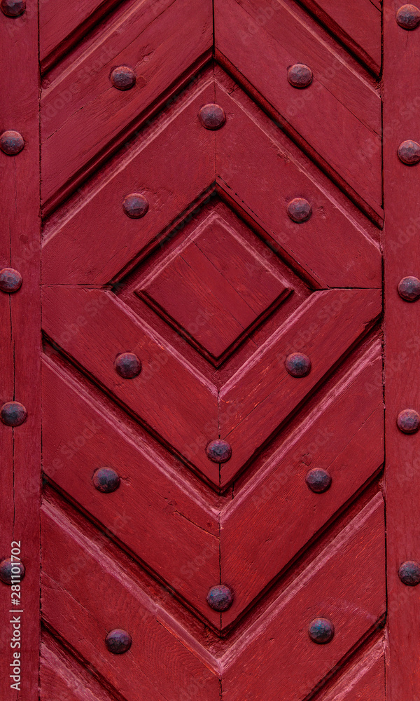 Close up of old vintage wooden door with metal furniture.  Red wooden fence background texture.