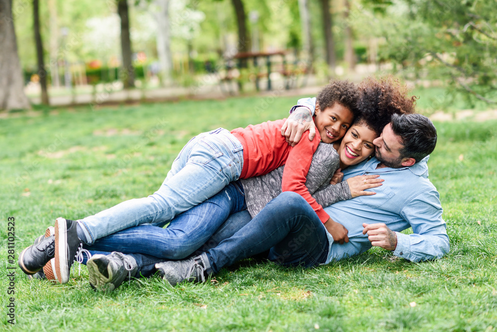 Happy family embracing, lying on grass in a park Happy family embracing, lying on grass in a park