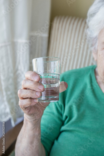wrinkled hand of a senior person holding a glass of water