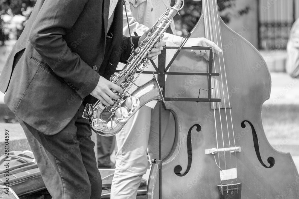 Obraz premium Street musician's hands playing saxophone and double-bass in an urban environment.