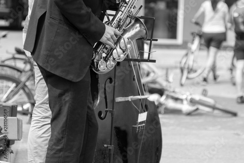 Street musician's hands playing saxophone and double-bass in an urban environment. Black and white picture.