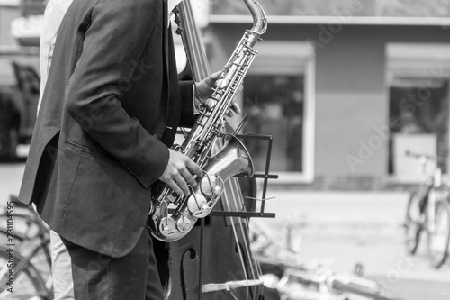Street musician's hands playing saxophone and double-bass in an urban environment. Black and white picture