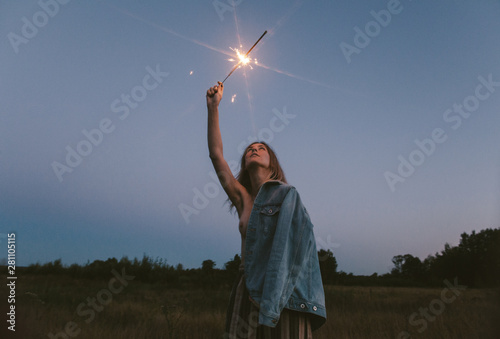 Topless woman with sparkler standing in field photo