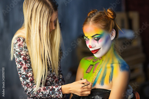 The artist applies body art to a lovely woman.