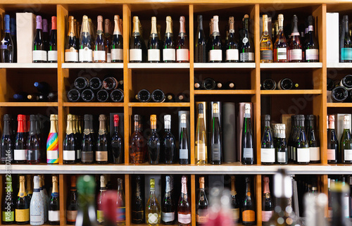 Rows of wine bottles on shelves in modern wine store waiting for customers photo