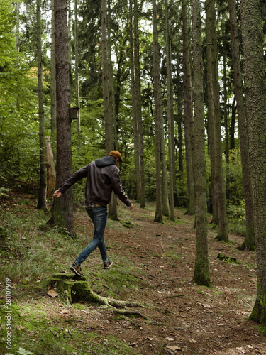 Man in green woods jumping on stub photo