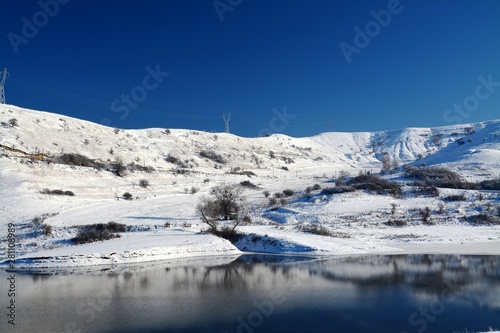 A lake near a hill covered with snow